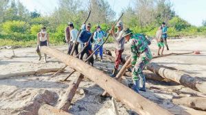 Satga TMMD Bersama Warga Desa Labuhan Pering Gotong royong Angkut Potongan Material yang Hanyut