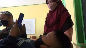 Ikuti Sunatan Massal TMMD, Anak Ini Sambil Bermain Gawai